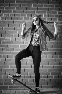 Genç hippi kız bir kaykay sürme. Kızlar kız şehirde bir kaykay ile yürüyüşe. Bahar spor bir kaykay ile sokakta