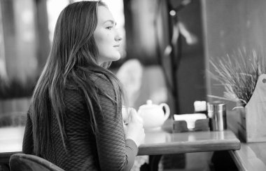 Bir kafede oturan ve tatlıyla çay içen güzel bir kız.