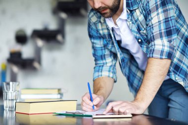 Oturma odasında oturmuş kitap okuyan neşeli bir gencin portresi. Elinde kitap tutan ve okuyan bir öğrenci..