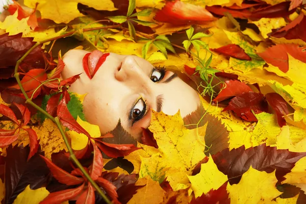 Artistic conceptual autumn portrait. Colorful leaves. Leaves of trees around emotional face. Autumn is coming.