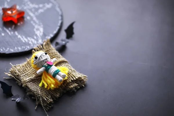 Voodoo Doll on a stone background with dramatic lighting. Mystic still life with voodoo doll, the tarot cards, books, evil candles and witchcraft objects. Divination rite.