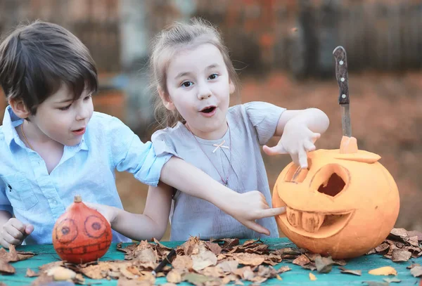 Autumn traditions and preparations for the holiday Halloween. A house in nature, a lamp made of pumpkins is cut out at the table.