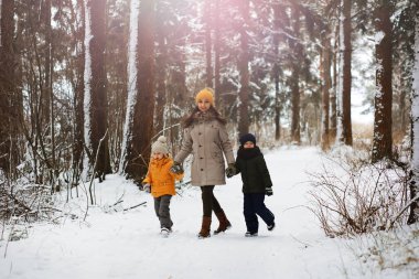Mutlu bir aile kışın dışarıda karda oynar ve güler. Şehir parkı kış günü.