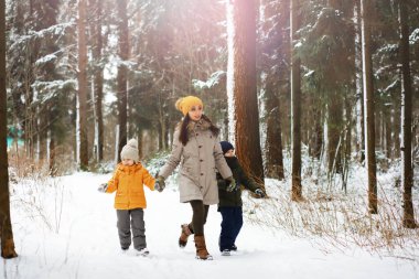 Mutlu bir aile kışın dışarıda karda oynar ve güler. Şehir parkı kış günü.