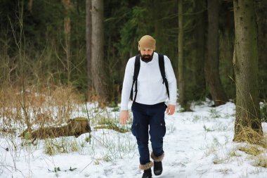 Palto ve İskoç kumaşlı yakışıklı bir adamın açık hava portresi. Kış ormanlarında sakallı adam.