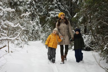 Mutlu bir aile kışın dışarıda karda oynar ve güler. Şehir parkı kış günü.