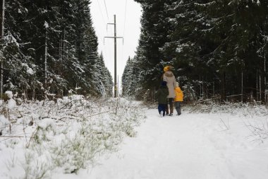 Mutlu bir aile kışın dışarıda karda oynar ve güler. Şehir parkı kış günü.