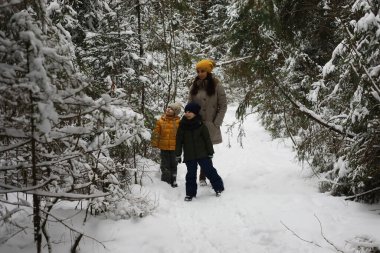 Mutlu bir aile kışın dışarıda karda oynar ve güler. Şehir parkı kış günü.