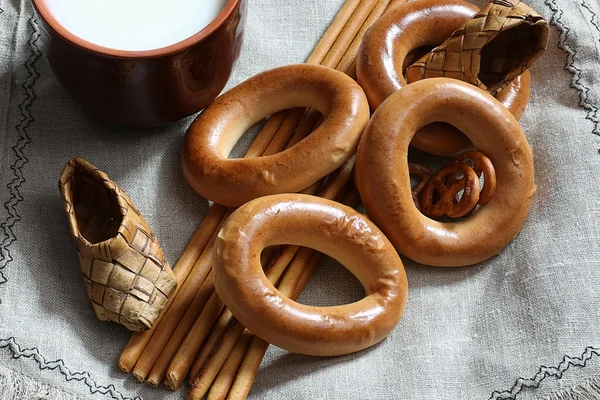 Food milk in a glass straw bagels and pretzels on flax background — Stock Photo, Image