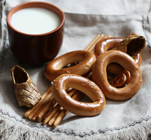 Food milk in a glass straw bagels and pretzels on flax background — Stock Photo, Image