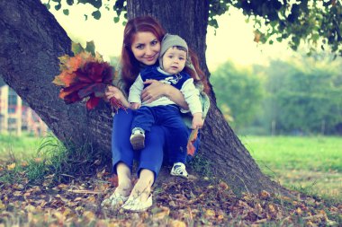 Kızıl saçlı kız oğlu ile sonbahar yaprakları