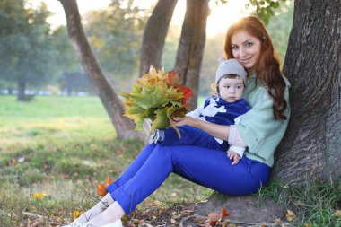 Kızıl saçlı kız oğlu ile sonbahar yaprakları