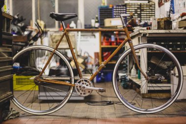 Eski ve paslı tek vitesli bisiklet ahşap bir atölyede oturuyor..