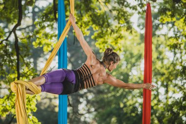 Güneşli bir günde Tivoli Parkı, Ljubljana 'da ağaçlardan sarkan iplerle hareket eden hava ipek sanatçısı.