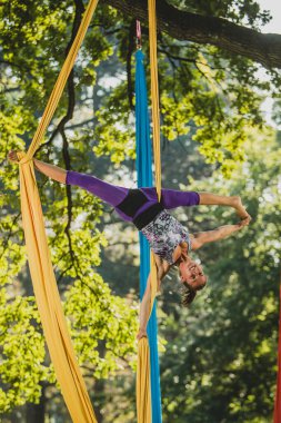 Güneşli bir günde Tivoli Parkı, Ljubljana 'da ağaçlardan sarkan iplerle hareket eden hava ipek sanatçısı.