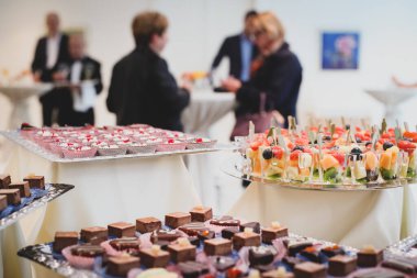 Bir iş resepsiyonunda servis tabağında çikolata, kek ve meyve gibi farklı tatlılar koleksiyonu..