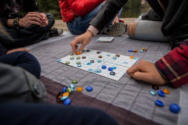 Bir grup farklı insan açık havada gölün yanında oyun oynuyor..