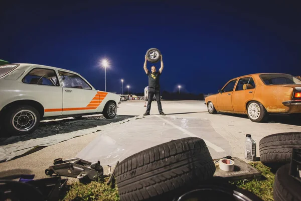 Homem Segurando Uma Roda Carro Acima Sua Cabeça Entre Dois — Fotografia de Stock