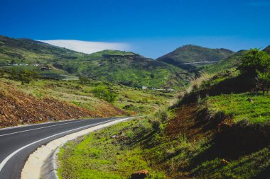 Pico do Fogo 'ya giden kıvrımlı yol, Cabo Verde adalarındaki Fogo adasındaki volkan, otlarla kaplı tepeler.