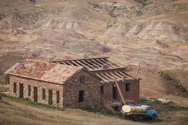 Panorama of a deserted house near David Gareja monastery. Old tanker truck is visible. Lunar like scenery in the background.
