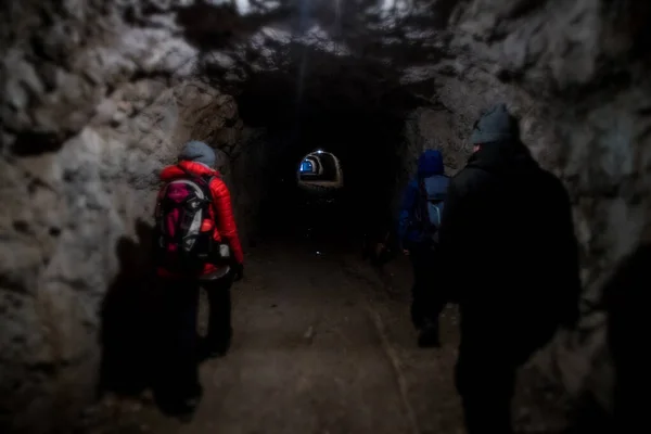 一群徒步旅行者正穿过山下一条人工建造的隧道 隧道是在第一次世界大战期间在斯洛文尼亚博弗茨周围的山上建造的 — 图库照片