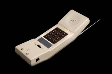 80 'lerden kalma eski bir beyaz kablosuz telefon, siyah üzerine izole edilmiş. Görünür kahverengi klavye ve gümüş anten.