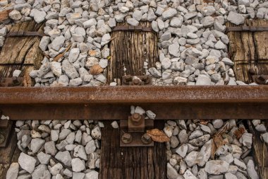 Eski demiryolu uyuyanları, derin çukurlu ve kuru odun ve pasla kaplı bir tren rayı ya da tırabzan..