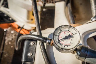 Dış motorun alt ünitesine, şanzımana hizmet veriyorum. Arka planda çalışan ve görünen basınç göstergesi ile, bir motorun dişli kutusunun mühürlenmesi test ediliyor.