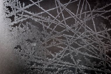 Pencerenin camındaki buz deseni. Donmuş buz, cam pencerenin soğuk havası sırasında oluşuyor. Siyah arkaplan.