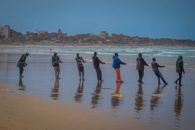 DAKAR, SENEGAL, FEBRUARY 18 Şubat 2017: Afrika 'nın Senegal kentindeki Yoff' un pitoresk plajında balıkçı ağıyla halatı sudan çıkaran yerel balıkçılar.