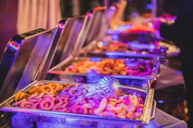 self servis büfesi. Akşam yemekleri yemek servisi. Akşam yemeği konsepti. Parti akşamı renkli ışıklandırmalı açık büfe, kaşıklı tabaklardan birine odaklan..