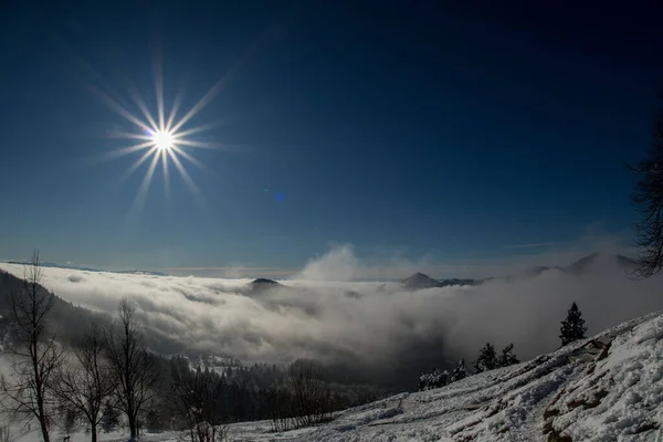 太阳在山顶上耀斑 山谷中的雪山和雾清晰可见 — 图库照片