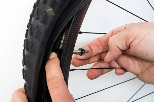 Bicycle tube repair. A hand of a person is installing a presta valve on a tubeless carbon mountain bike wheel.