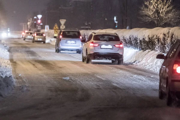 A row of passenger cars in a row on a daily commute on a snowy road during early morning. Early morning commute in snowy conditions with SUV and other passenger cars.