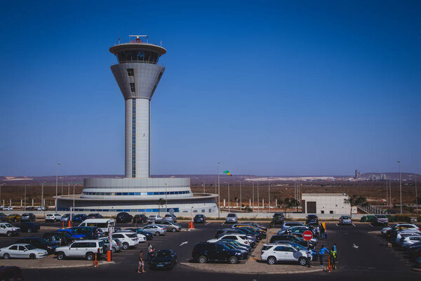 DAKAR, SENEGAL, FEBRUARY 22 2018: Control tower on the new Blaise Diagne airport in Dakar, Senegal on a sunny day. Some people, security guards and cars are seen parked on the parking lot in front.