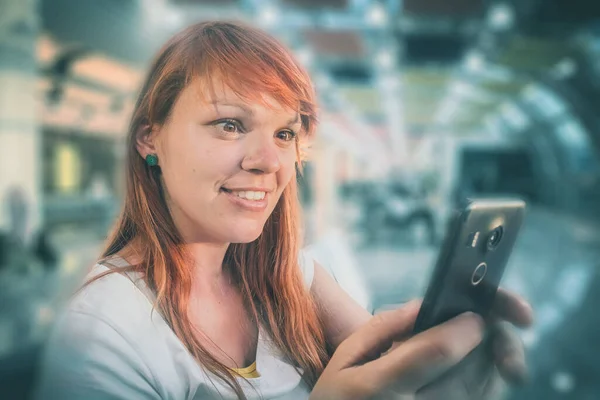 Een Jonge Roodharige Vrouw Zit Het Vliegveld Met Een Smartphone — Stockfoto