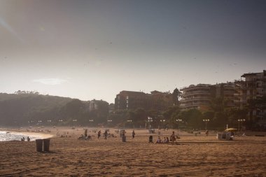 İspanya 'nın Lloret de Mar bölgesinde Fenals plajı. Akdeniz 'de bir plajda puslu bir öğleden sonra. Bazı insanlar plajda görülürler. Batan güneşten güçlü bir ışık.
