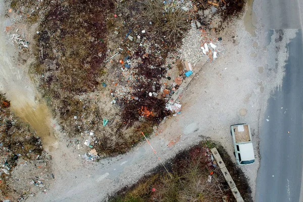 An illegal dumping ground of construcion trash seen from above. Concept of illegal dumping of trash with a visible delivery van on the side of the road. Problem of illegal dumping.