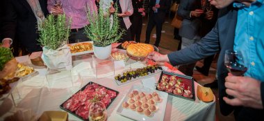 Bir ziyafette insanlar, bir gala partisinde tabaktan et, zeytin ve ekmek gibi farklı yiyecekler alıyorlar..