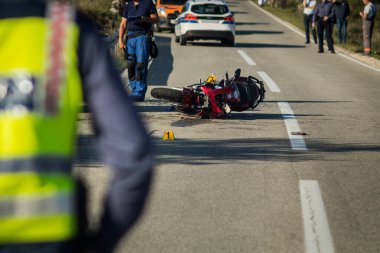 Öğleden sonra açık bir yolda araba ve kırmızı spor motosiklet kazası. Çalışanlar ve polis, arkada bir trafik binası kuyruğuyla kaza alanında görüldü. Yıkılmış minibüs ve motosiklet.
