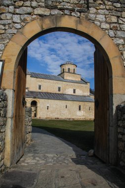 Güneşli bir günde Sırbistan 'ın Novi Pazar kentine yakın bir manastır olan duvardaki kemerden Sopocani manastırına doğru bakıyor.