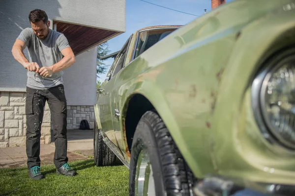 Kalça Sakallı Genç Bir Adam Eski Yeşil Bir Arabayı Temizlerken — Stok fotoğraf