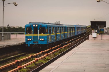 Ukrayna 'nın Kiev kentindeki metro istasyonuna mavi ve sarı renkli metro treni yaklaşıyor. Platformda bir yolcu görülüyor..