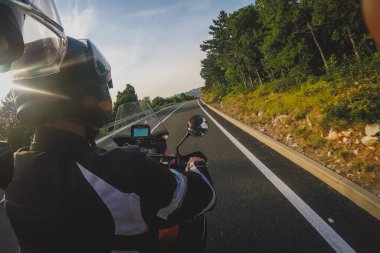 Modern macera motosikletinin arka koltuğundan bakış açısı akşam saatlerinde Hırvat kıyı yolunda seyrediyor..