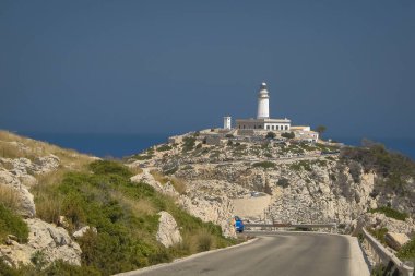 Güneşli bir yaz gününde Mallorca, İspanya 'daki kaptan Formentor' daki deniz fenerine doğru bakıyorum. Ön planda bir sürü kaya ve deniz fenerine giden bir yol var..