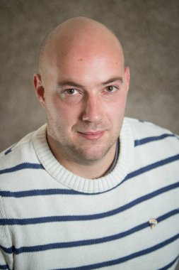 Gri arka planda çizgili süveter giyen modern iş adamı portresi. Genç iş adamının gayri resmi portresi.