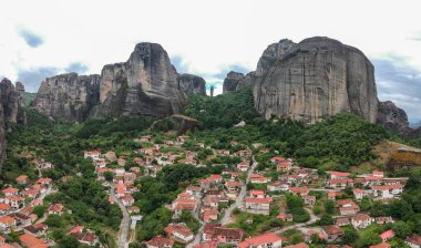 Köyün yukarısındaki Meteora Manastırı Panoraması. Güzel manzaralı panoramik manzara, Meteora, Thessaly, Yunanistan ve Avrupa 'da bulutlu bir günde dev bir taş sütunun tepesinde antik geleneksel Yunan binası.