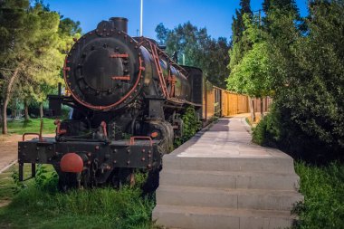 Geceleri Yunanistan 'ın Kalamata kentindeki bir parkta demiryolu sergisi olarak park edilmiş eski bir buhar treni. Peleponese adasındaki bir parkta arabalı buharlı lokomotif.