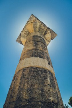 Doric Order sütunu veya sütunun dikey bir fotoğrafı, Yunanistan 'ın Olympia kentinin antik arkeolojik sahasında çekilmiş bir fotoğraf, güneşli bir günde güneş direk sütunun arkasında parlıyor