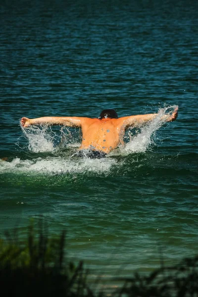 晴れた日にウクライナのキエフの近くの湖で背中から蝶のストロークを泳いで見た男 — ストック写真